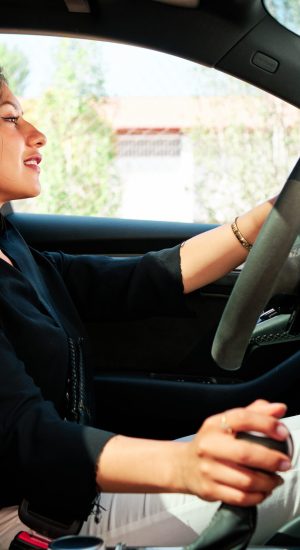 young latin woman driving luxury car